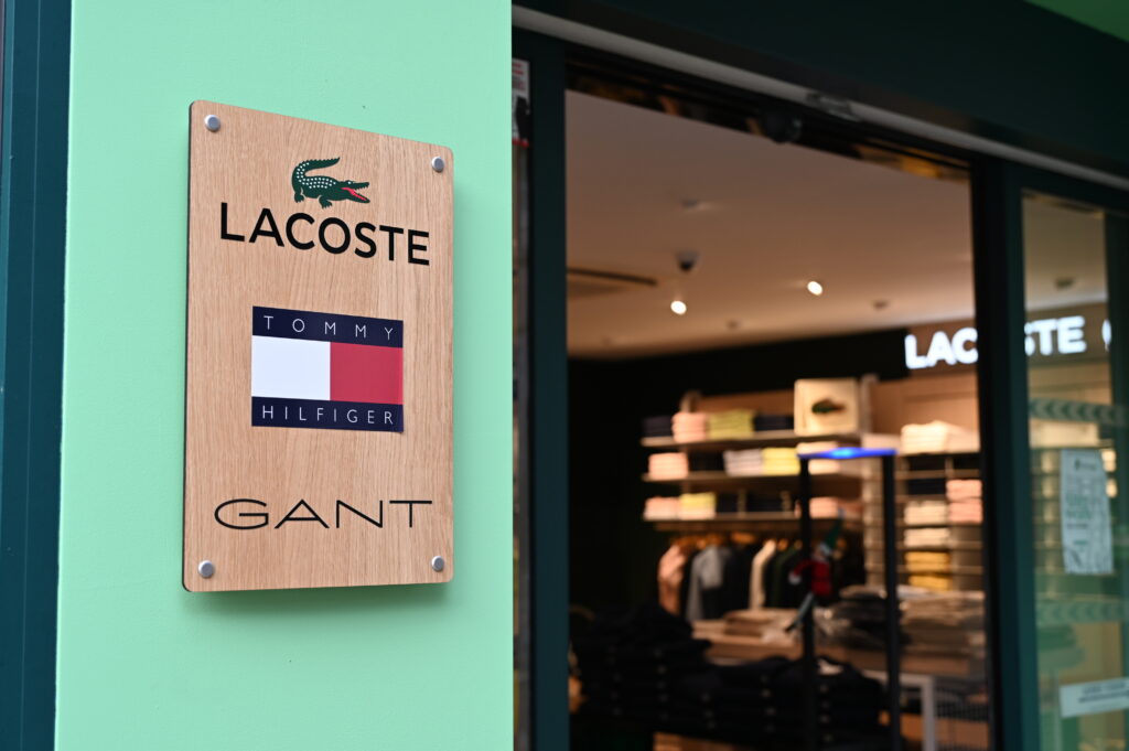 Plaque signalétique Héritage Rochon présentant les marques Lacoste, Tommy Hilfiger et Gant à l’entrée de la boutique